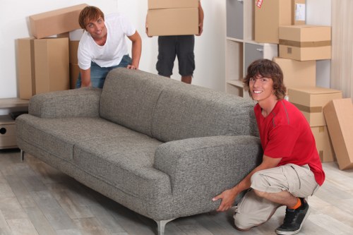 Local removals crew handling furniture in a Bow flat with narrow access